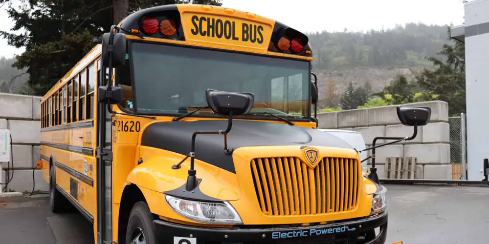 A closeup of the front of a new electric school bus on a cloudy day.