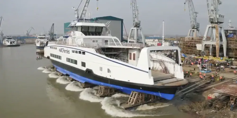 An electric BC Ferry is launched into the water from the dock where it was built.