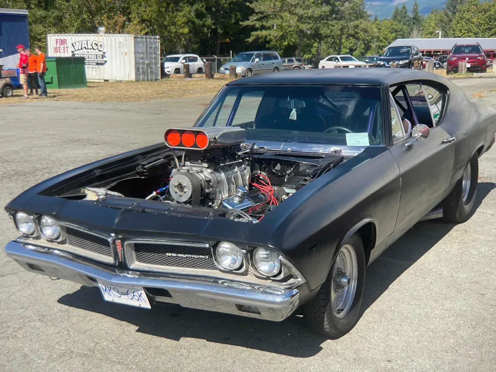 A classic Beaumont, painted black, with no hood. It’s parked and has a compressor mounted in the engine.