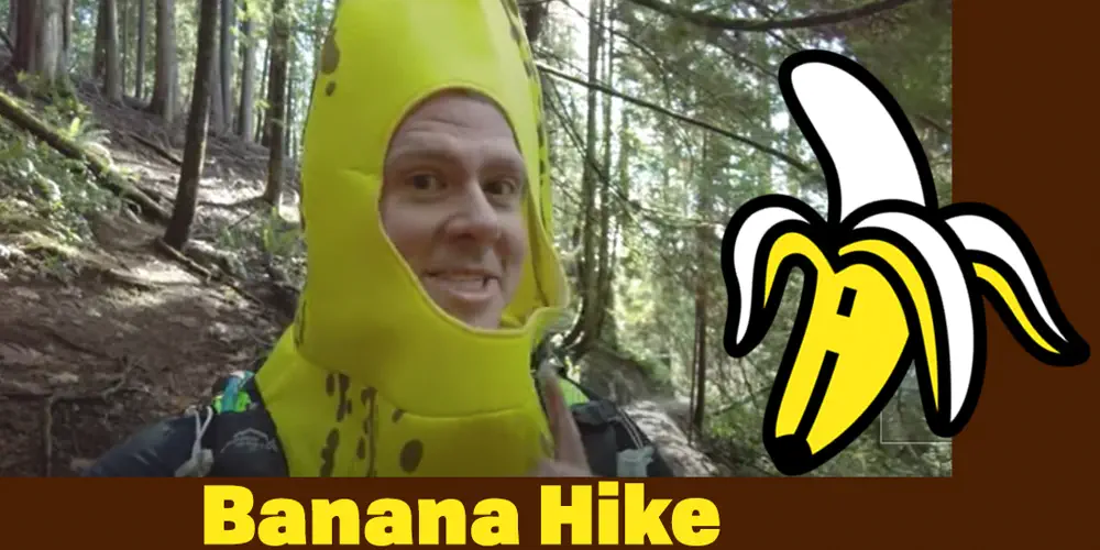 A man takes a selfie on a mountain trail while wearing a banana costume.