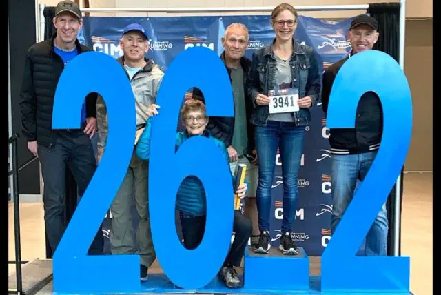 Members of the Comox Valley Road Runners smile for the camera with a sign that reads 26.2.