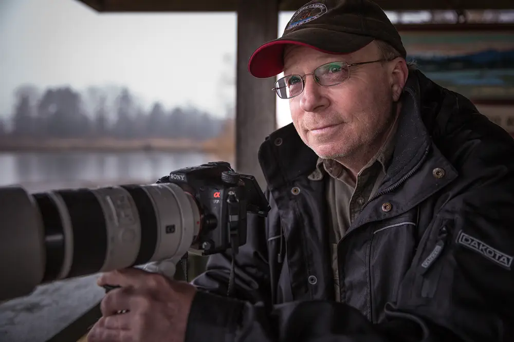 Fred Fern sits at a window with his giant camera.