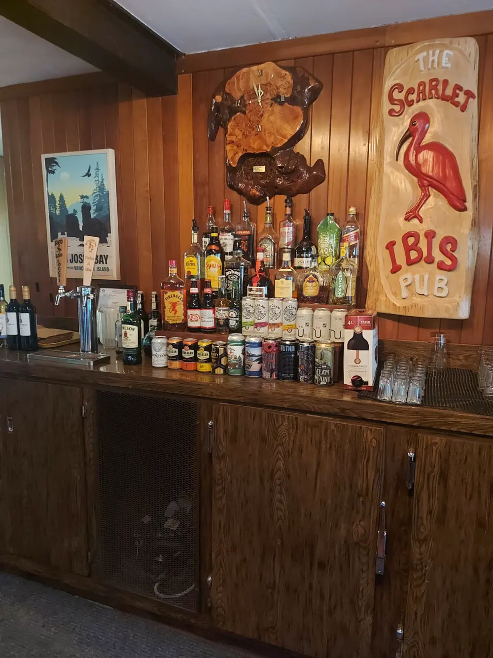 The bar selection at the Scarlet Ibis pub. The walls have wood panelling and vintage plaques. It has a very cozy feel.
