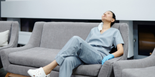 Photo of a tired healthcare professional resting on a grey couch