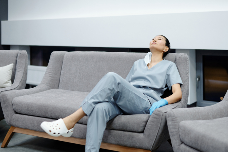 Photo of a tired healthcare professional resting on a grey couch