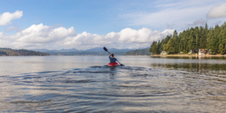 Person on kayak under blue and white sky