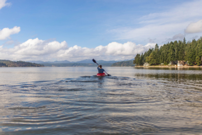 Person on kayak under blue and white sky