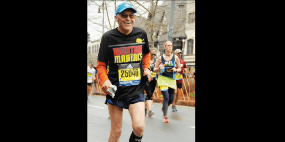 Ken Richardson running a marathon with a big smile on his face and wearing a Marathon Maniacs t-shirt.