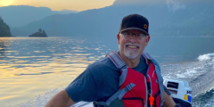 Terry Mazzei boats on a lake with mountains in the background.