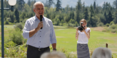 Erin O'Toole speaks into a microphone at an outdoor gathering on a sunny day.