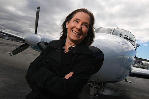 A portrait of Teara Fraser smiling in front of an airplane.