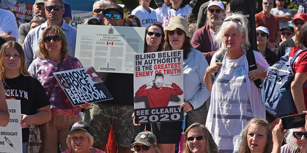 White people hold up anti-vaccine signs made by graphic designers.