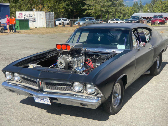 A classic Beaumont, painted black, with no hood. It's parked and has a compressor mounted in the engine.