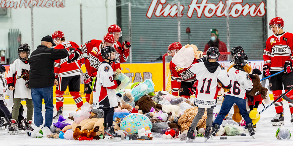 The Bulldogs team and minor hockey players pick up stuffies that were tossed onto the ice after a goal.