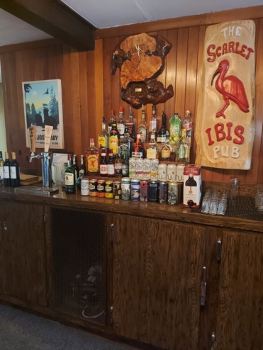 The bar selection at the Scarlet Ibis pub. The walls have wood panelling and vintage plaques. It has a very cozy feel.