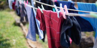 Colourful clothes hang on a clothes line on a sunny day.