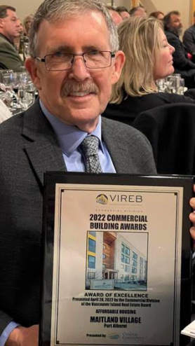 Mike Ruttan accepts the 2022 Vancouver Island Real Estate Board Award of Excellence for Affordable Housing.