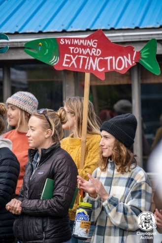 Young people stand with a sign that reads "swimming toward extinction."