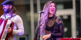 A duo sing and play accordian under purple lights at the Filberg Festival.