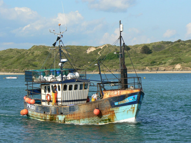 A small fishing boat sails by on a sunny day.