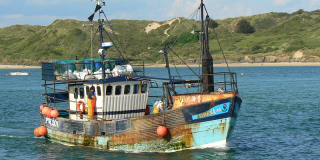 A small fishing boat sails by on a sunny day.