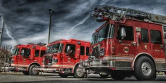 Three Courtenay fire trucks sit parked against a moody sky.