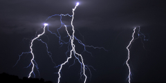 Lighting strikes against a pitch black sky.