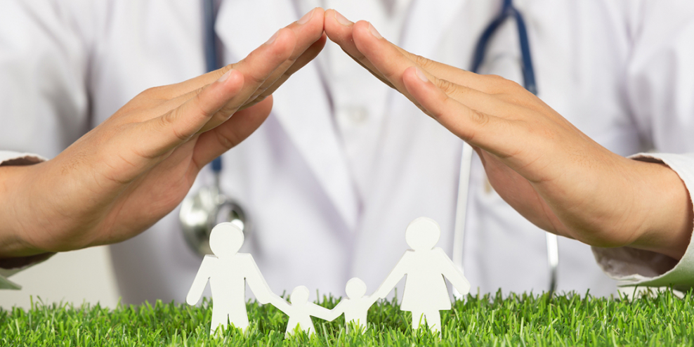 A doctor holds their hands over a paper cut-out of a family.