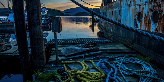 Early morning light hits coiled fishing ropes on a dock with hills in the background.