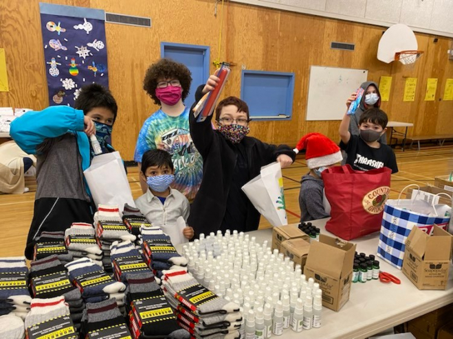 Kids cheer in front of a table full of warm clothes that have been donated to EDAS.