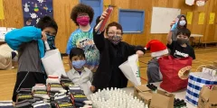 Kids cheer in front of a table full of warm clothes that have been donated to EDAS.
