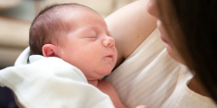 A mother holds a tiny sleeping baby.