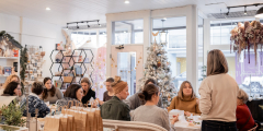 People sit around a large table making crafts in the festively decorated Wildflower Mercantile.