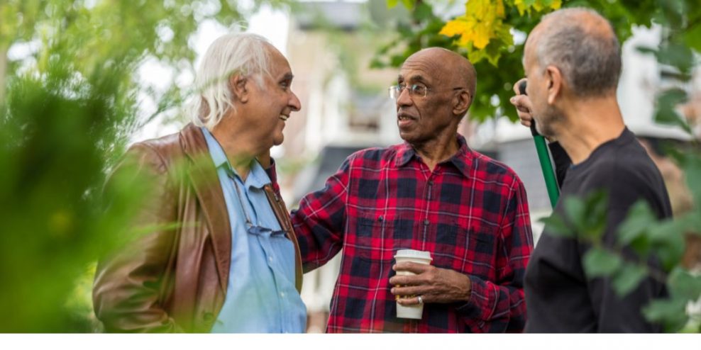 Three older gentleman have a chat outside.